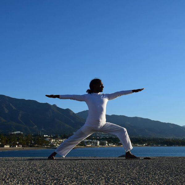 Silhouette of a person in a yoga pose against a sunrise.