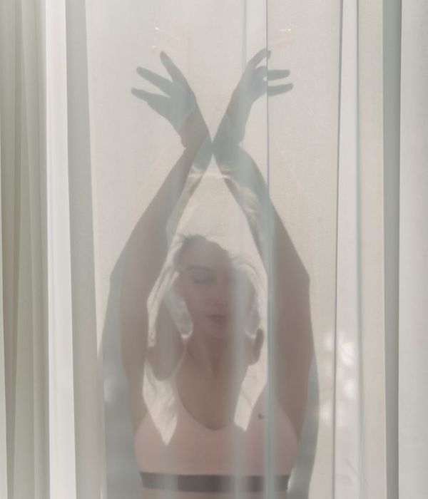 Woman in a calm yoga pose in a dark room with soft light.